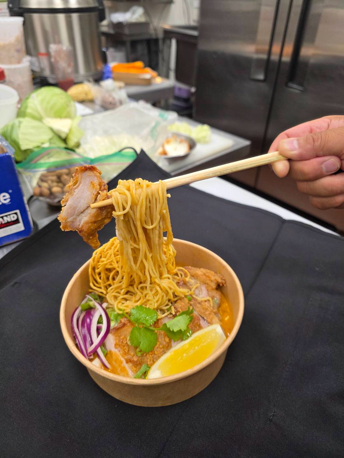 A bowl of khao soi being served in the Thai Sabb kitchen
