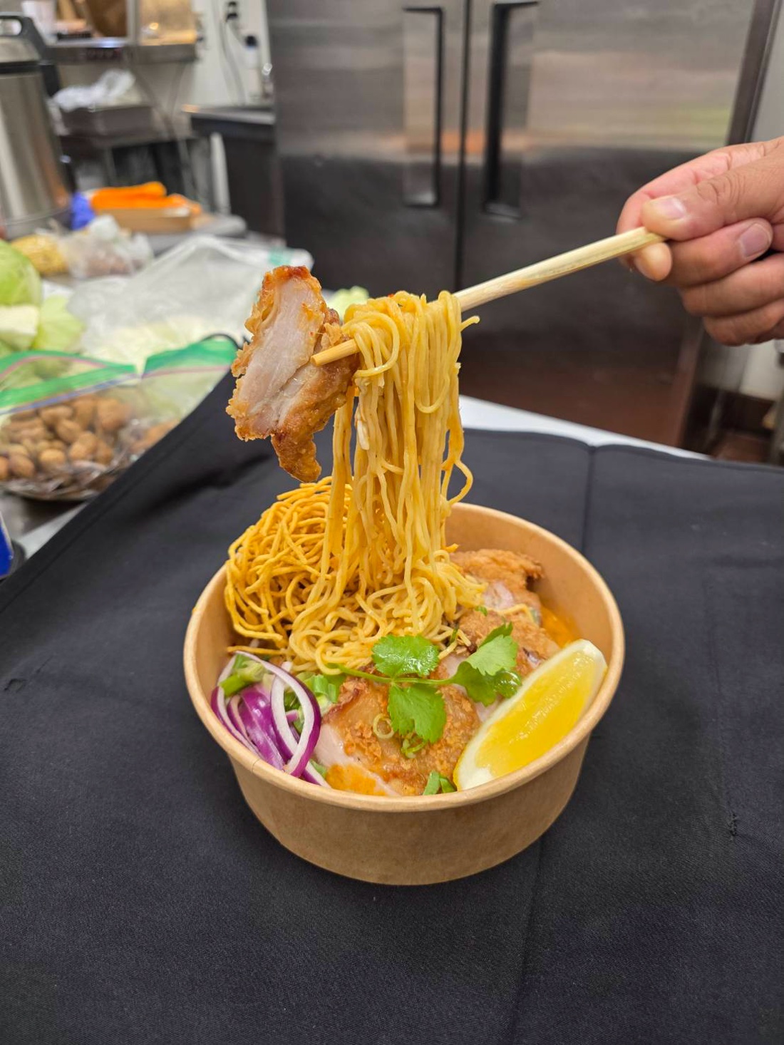 Crispy egg noodles being lifted out of a bowl of khao soi